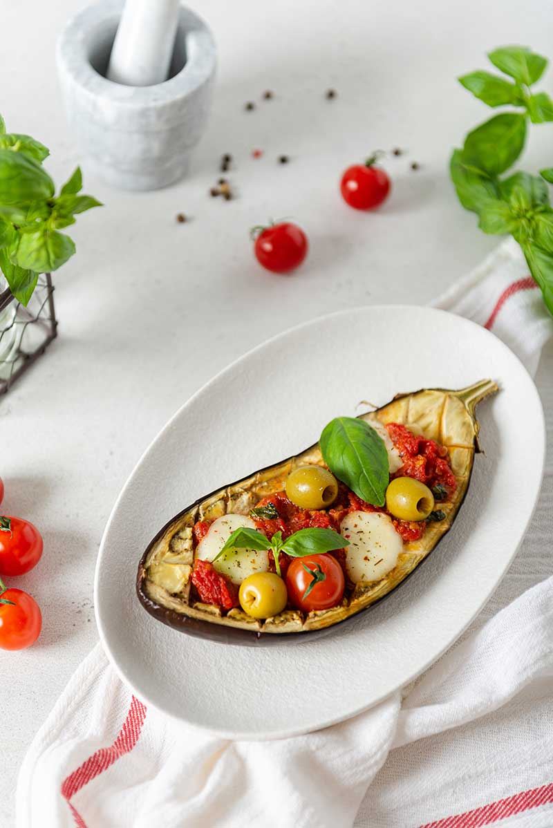 Italian traditional dish with eggplant, tomatoes, olives, mozzarella and basil