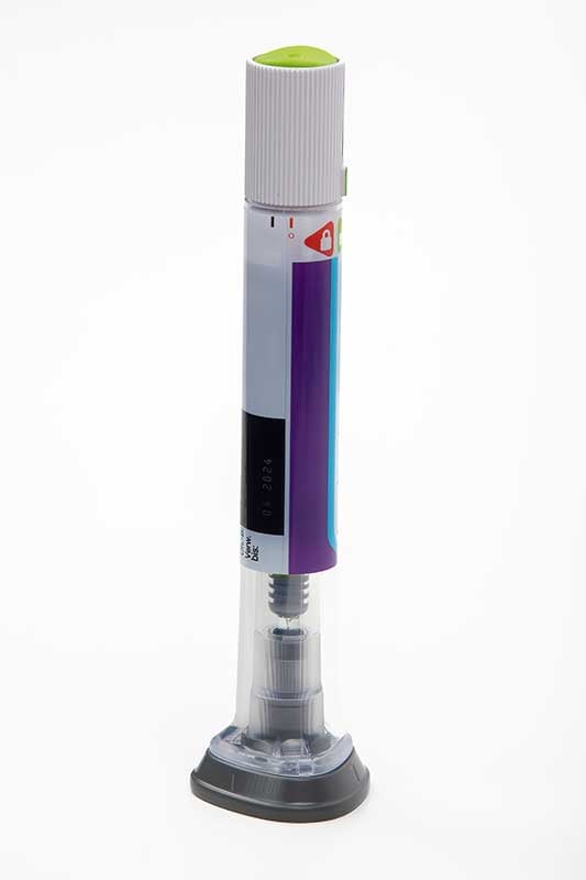 A gray and purple injection pen with a green cap and a transparent bottom section showing its internal mechanism.