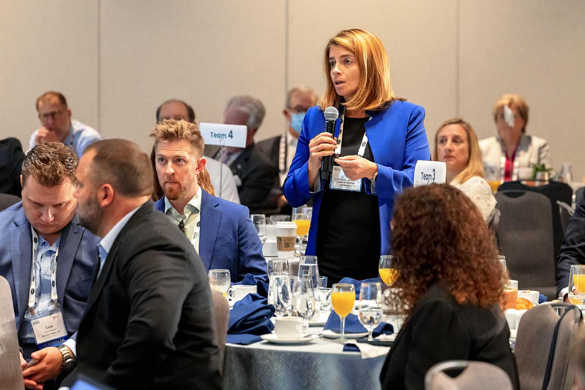 A woman holding a microphone addresses a question during a Washington Conference session.