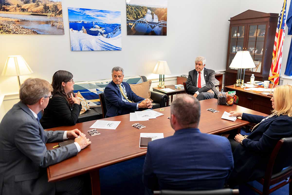 Six people sit around the desk in a private office at the Washington Conference in an intense discussion.