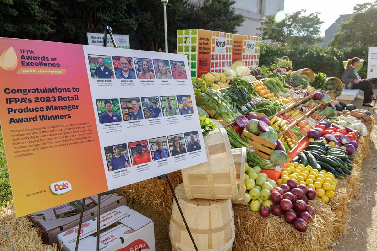 An outside display featuring fresh produce. To the side of the produce is a board announcing IFPA's 2023 Retail Produce Manager Award winners.