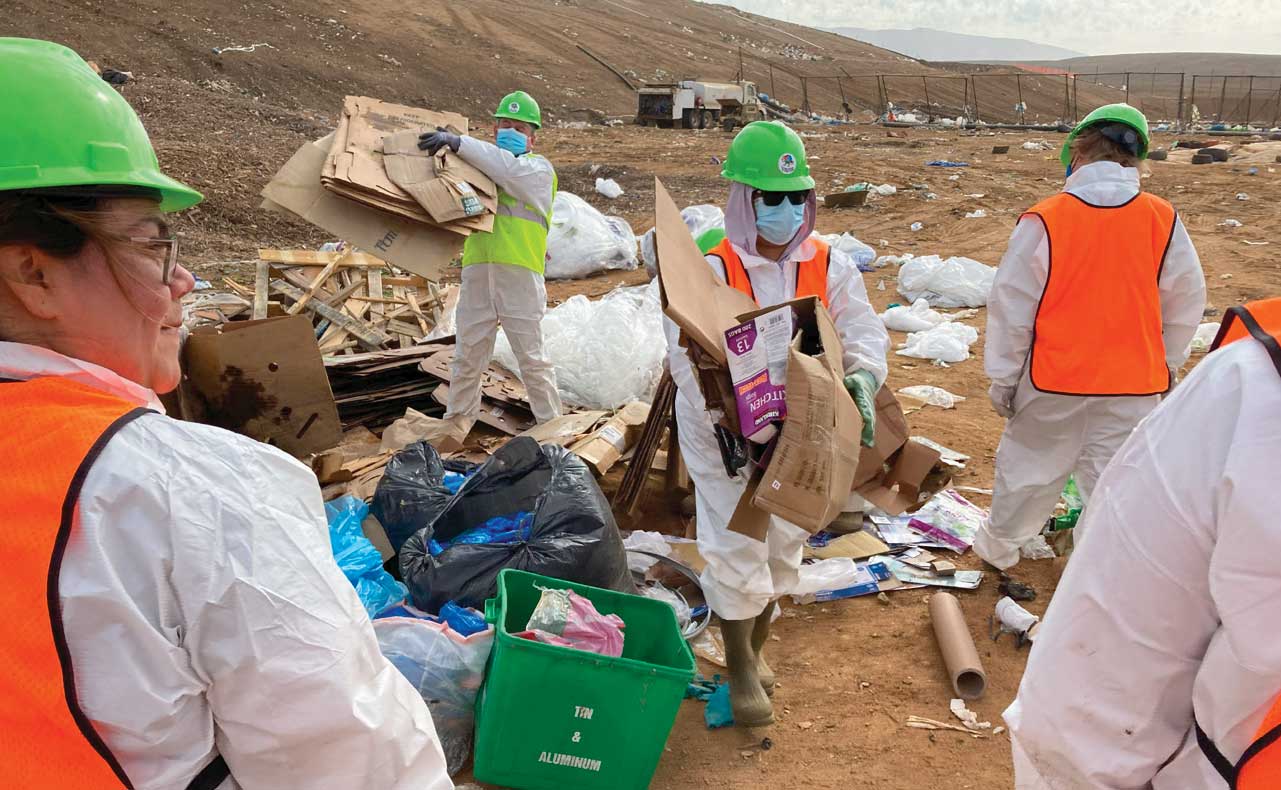 People dressed in safety vest, masks and hard hats conduct Misionero waste audit